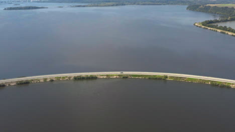 Cars-driving-on-narrow-Věstonice-reservoir-causeway,-drone-shot