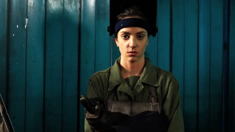 female welder standing with arm crossed in workshop