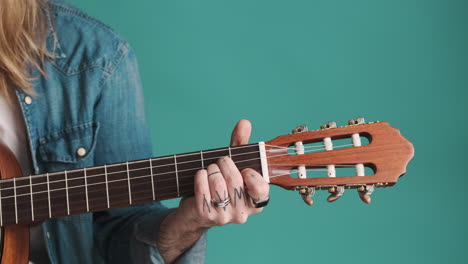 caucasian young man playing guitar on camera.