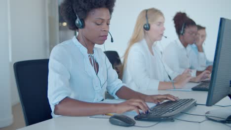 equipo de operadores de centros de llamadas en auriculares sentados en fila