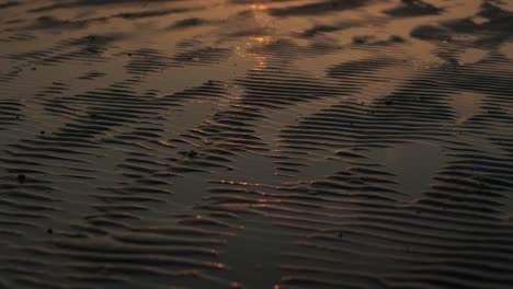 Wellen-Im-Sand,-Verursacht-Durch-Meereswellen,-Die-Im-Sonnenuntergang-Glänzen