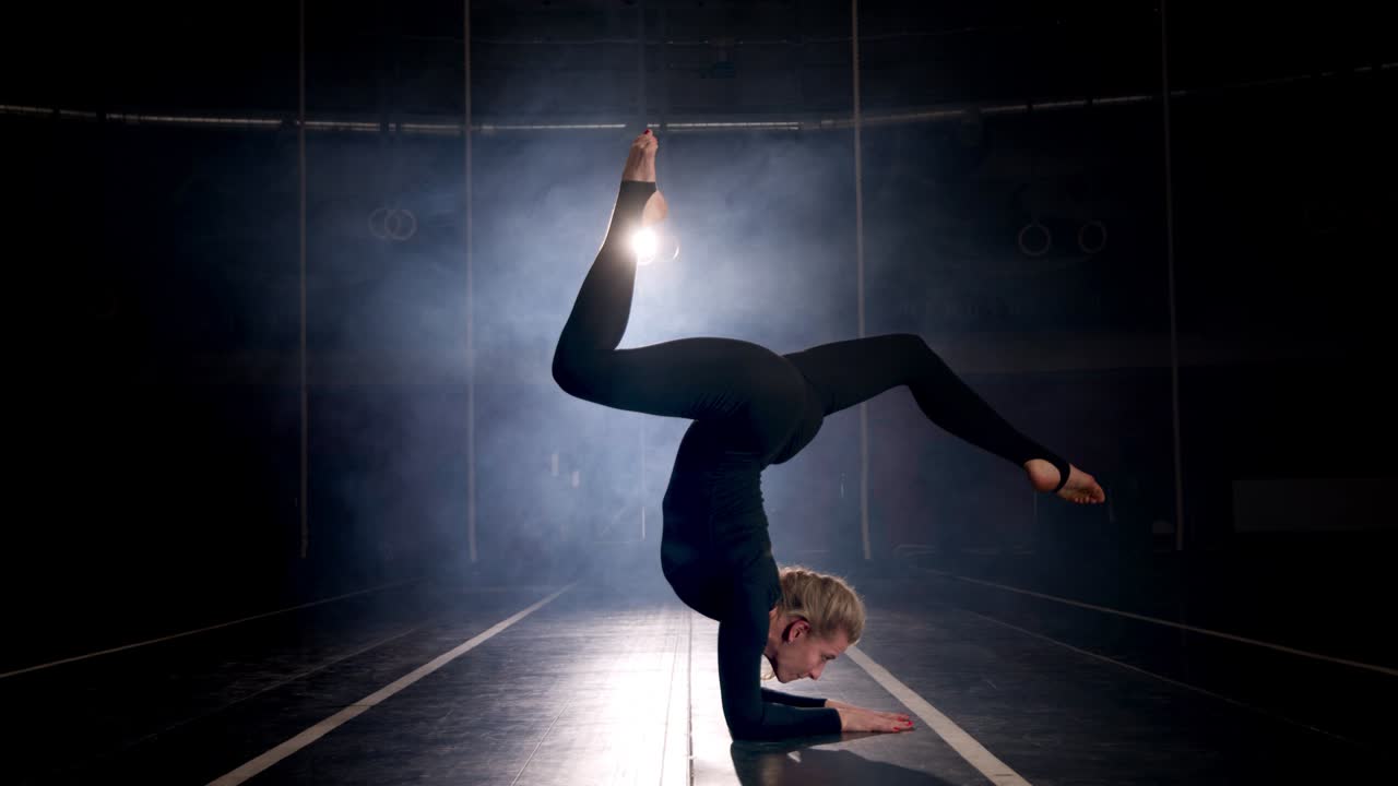 silueta de una gimnasta femenina actuando en el estudio de baile oscuro. mujer flexible