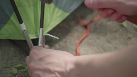 [close up] shot of someone pounding a tent peg into dirt