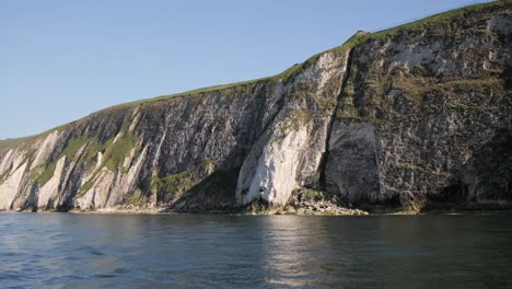 Rugged-cliffs-with-green-vegetation-meeting-the-calm-sea-under-a-clear-blue-sky