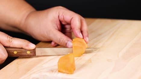 hands carefully chopping a persimmon into pieces