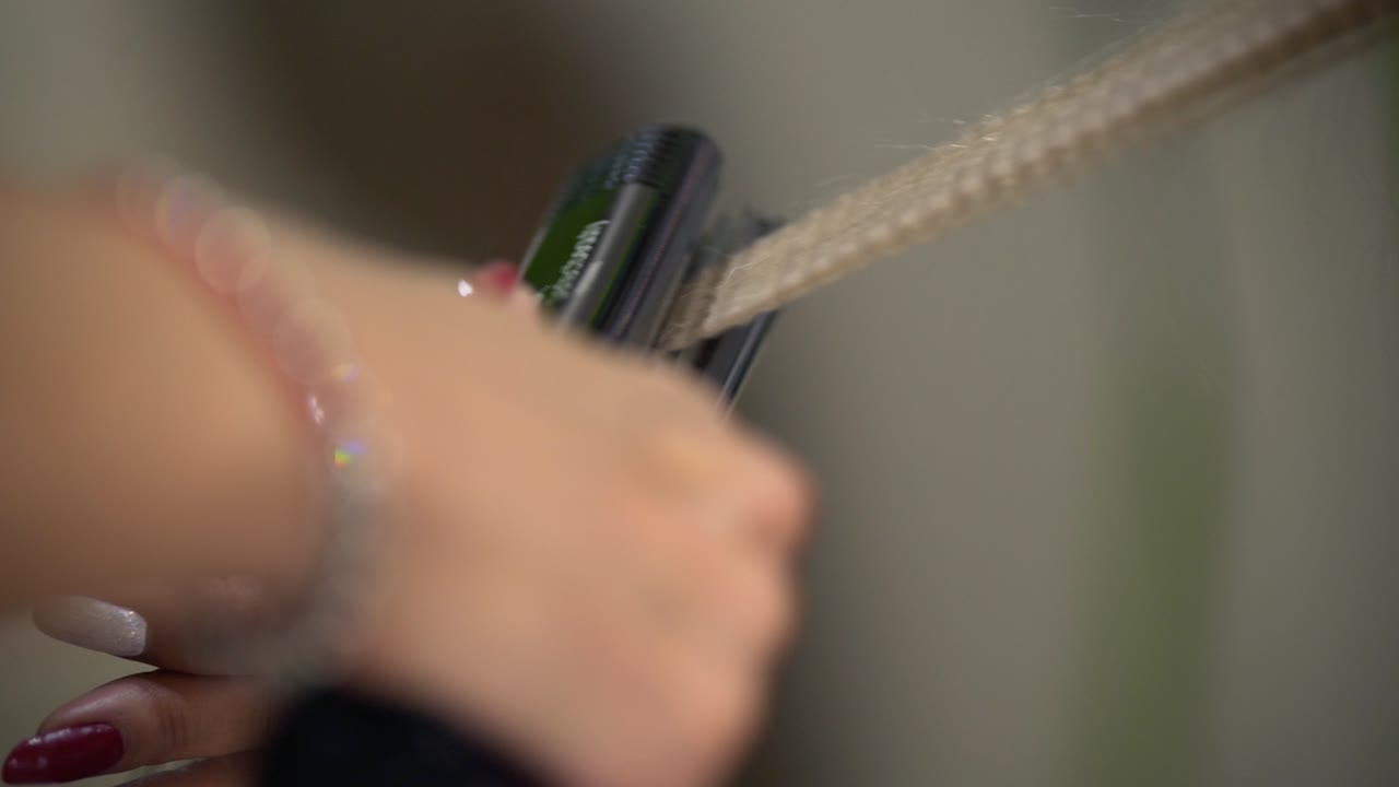 그녀의 등 뒤에 서서 컬링 아이언을 사용하는 젊은 아가씨와 전문 미용사