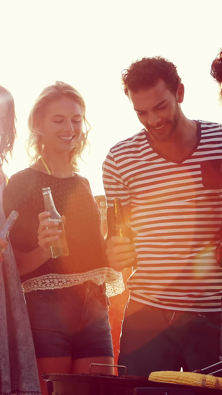 amigos felices sosteniendo cervezas y cocinando carne