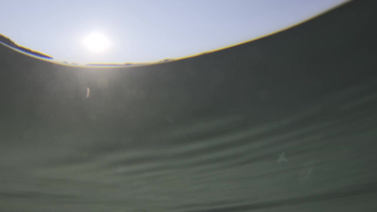 Underwater view showing the sun's surface reflection and light filtering through the tranquil ocean water, creating a serene ambiance
