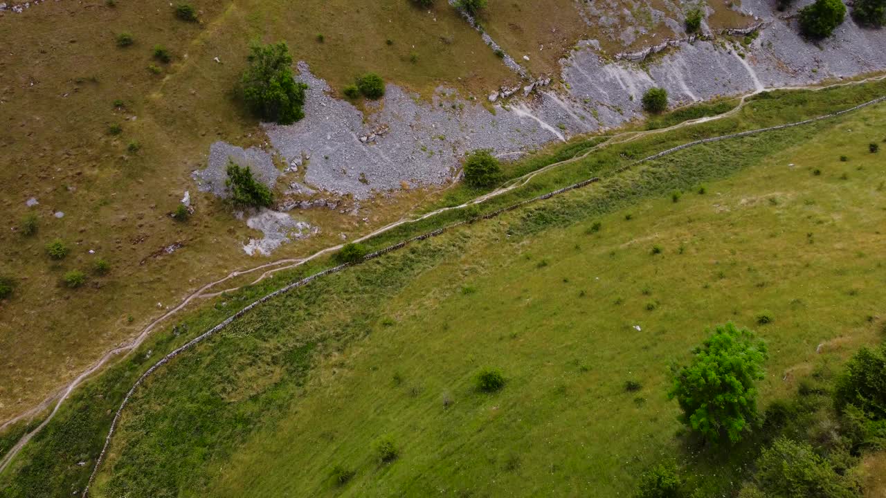 vista aérea de pájaro volando a través del vibrante valle de senderismo de pastizales en el campo rural del distrito pico
