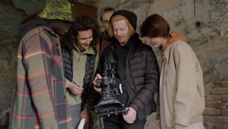 production team and cameraman laughing while reviewing a scene in a camera in a ruined building