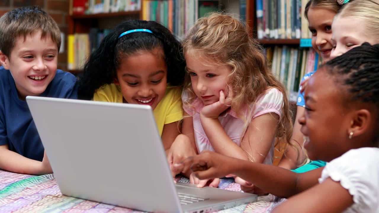 alumnos que usan el portátil juntos en la biblioteca