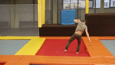 man performing acrobatic jumps on a trampoline in an indoor activity center