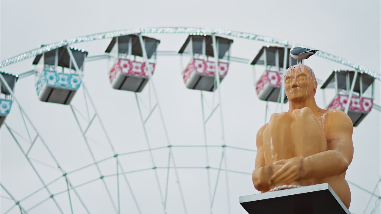 Nice, France - December 8, 2024: Conversation a Nice statue by Jaume Plensa at Place Massena with a ferris wheel on the background