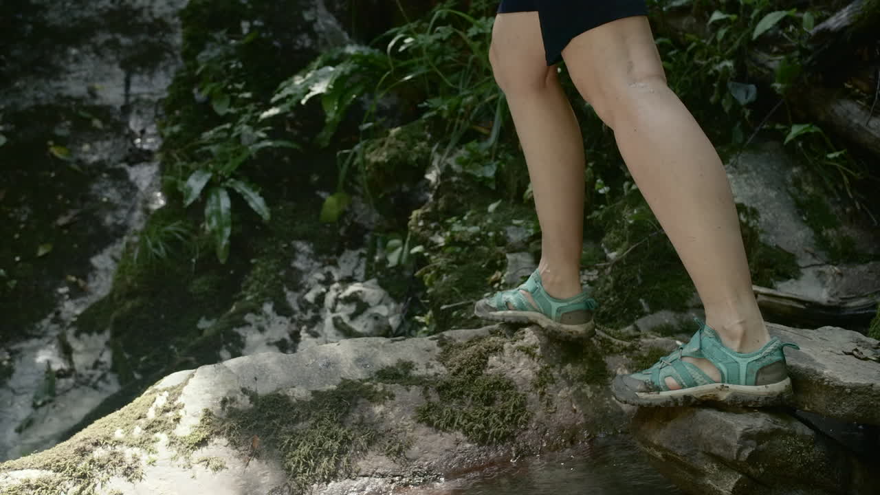 숲 의 폭포 를 가로질러 산책 하는 여자