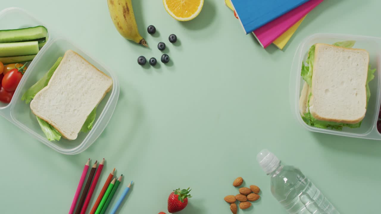 vídeo de un almuerzo sano envasado de frutas y verduras, con lápices de colores y cuadernos