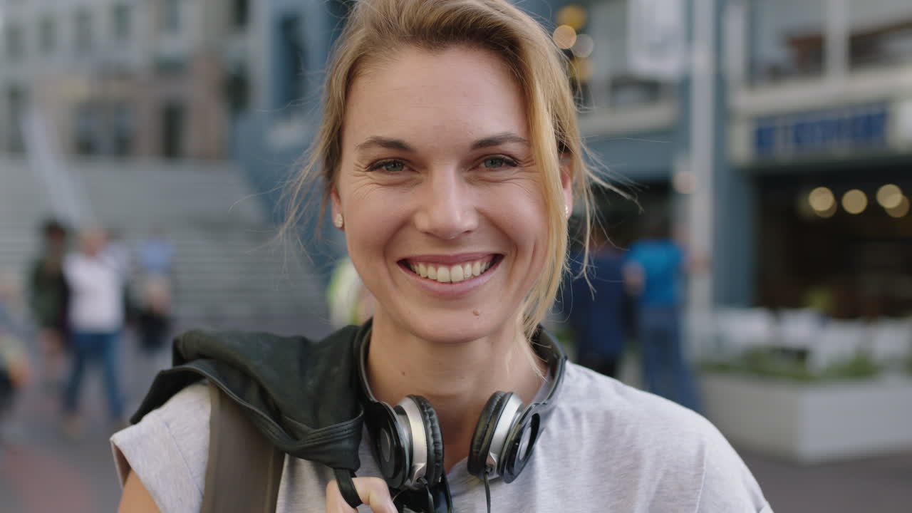 ritratto di una donna bionda indipendente sorridente felice ottimista che indossa cuffie sul marciapiede della città urbana