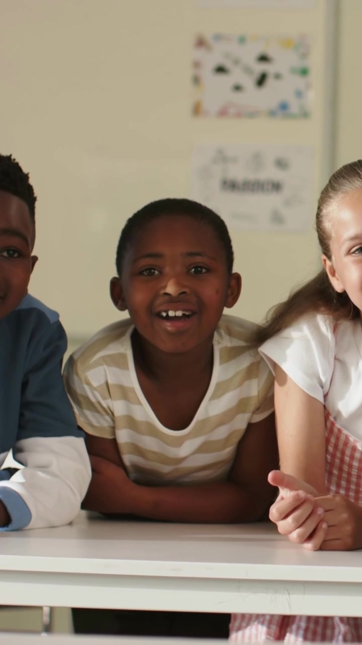 Center child opening mouth and smiling while peers leaning on white table during school song