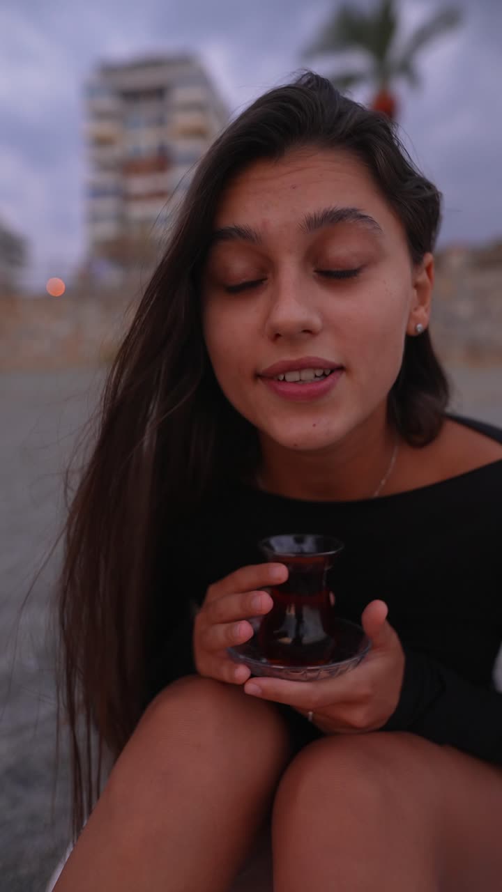 mujer disfrutando de té turco al atardecer en la playa