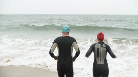 zwemmers in wetsuits in zeegolven