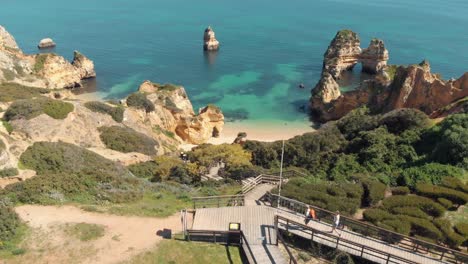 revelación de la playa de camilo sobre una colina empinada con una pasarela de madera, lagos, algarve, portugal - toma aérea de revelación