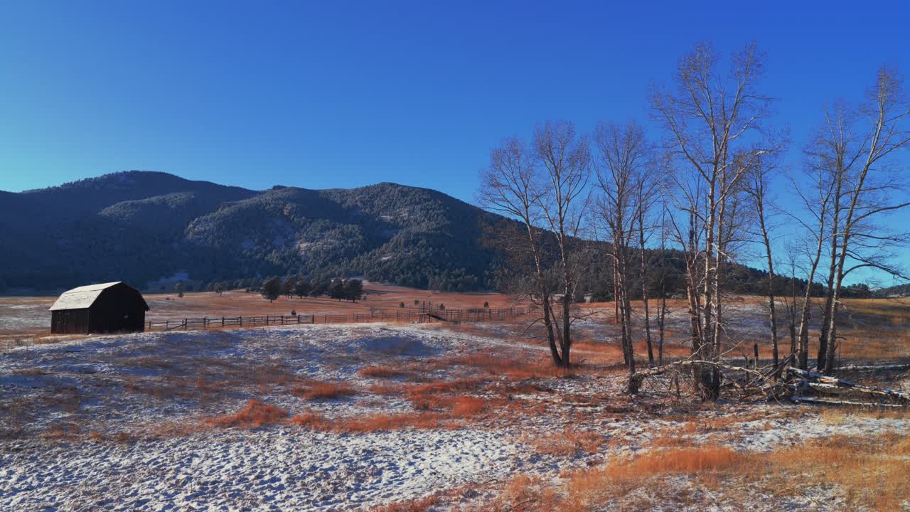 Bergren Peak Elk Meadow Park fienile rosso spazio aperto sentiero escursionistico tramonto soleggiato sempreverde Colorado drone aereo cielo blu pendici innevate valle foresta Front Range Montagne Rocciose paesaggio pan left