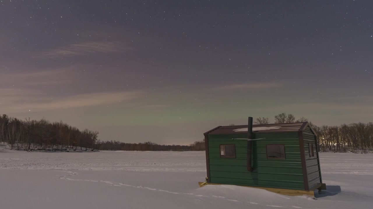 Fenomeno naturale: aurora boreale scintillante sopra una casa da pesca sul ghiaccio nel cielo notturno del Wisconsin, USA. Timelapse.
