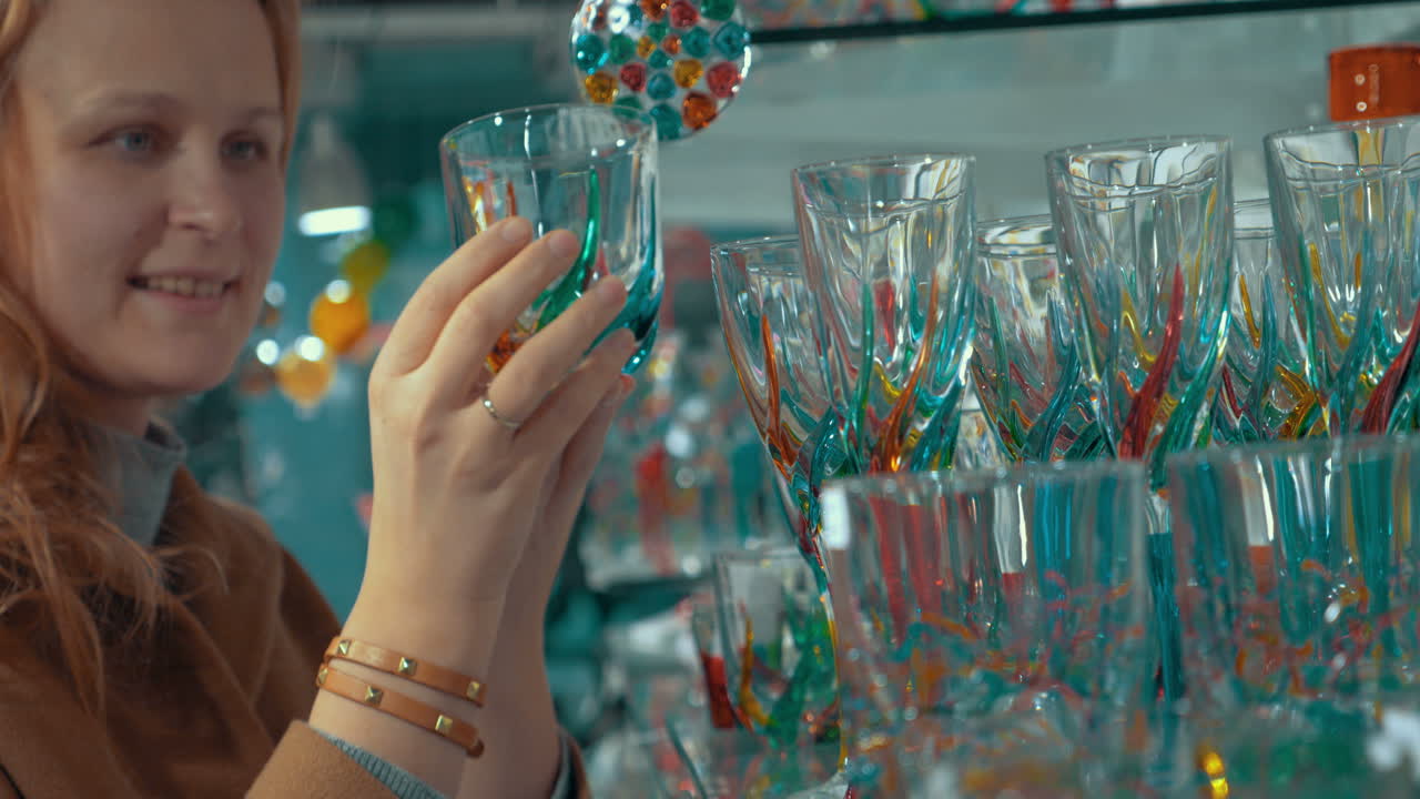 Mujer joven mirando cristal veneciano en la tienda