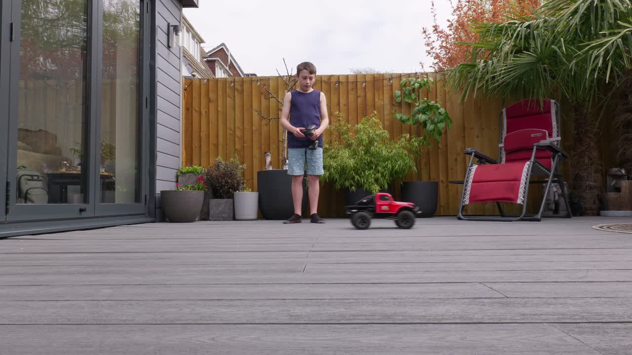 Young boy at home outdoors in the garden playing with his RC Car, Truck, 4 x 4