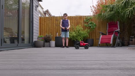 niño en casa al aire libre en el jardín jugando con su coche rc, camión, 4 x 4