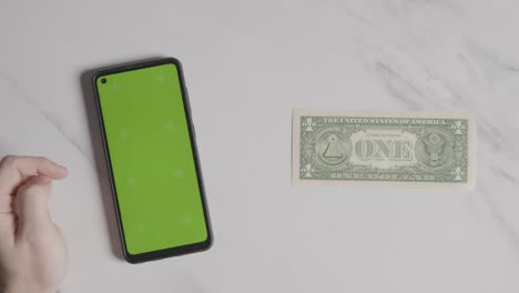 overhead currency shot of us 1 dollar bill next to person using green screen mobile phone 1