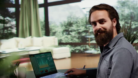 Young-man-sitting-at-desk-in-his-luxury-cabin-with-large-windows