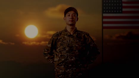 asian army soldier standing against with flag of the united states, sunset time. brave young servicemen wearing camouflage military uniform