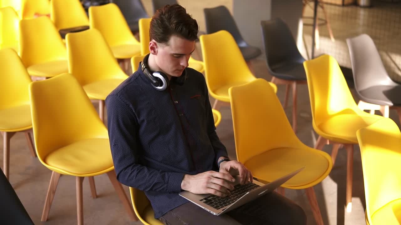 Young attractive male typing something on laptop. working indoors. Co-working space.