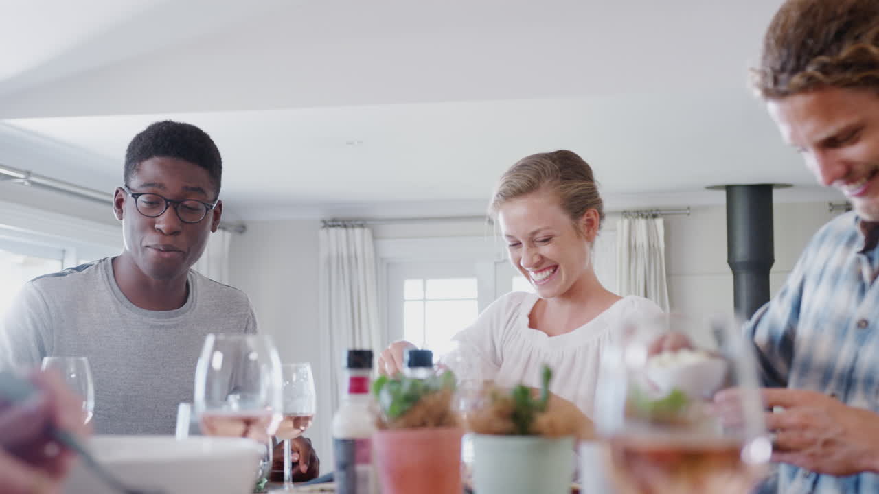 grupo de amigos jóvenes sentados alrededor de la mesa en casa disfrutando de la comida juntos