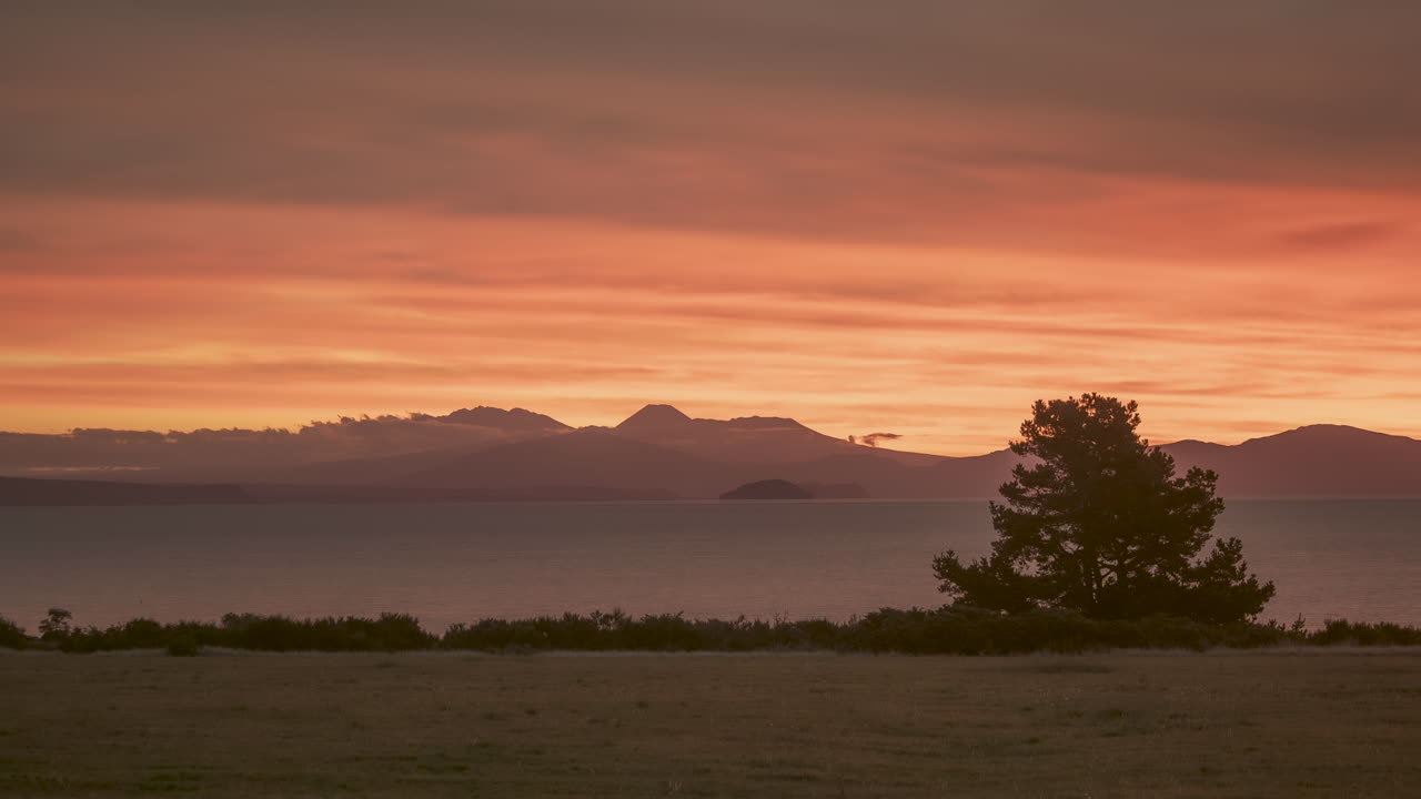 Wide timelapse capture of Lake Taupo at sunset, with glowing orange sky over volcanic silhouettes in New Zealand’s North Island