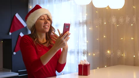 a girl in a new year's red suit in the kitchen leafs through a smartphone with a green screen with her finger