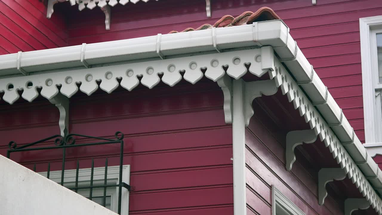 색 트림과 장식적인 지붕을 가진 빨간 나무 집의 모이의 클로즈업