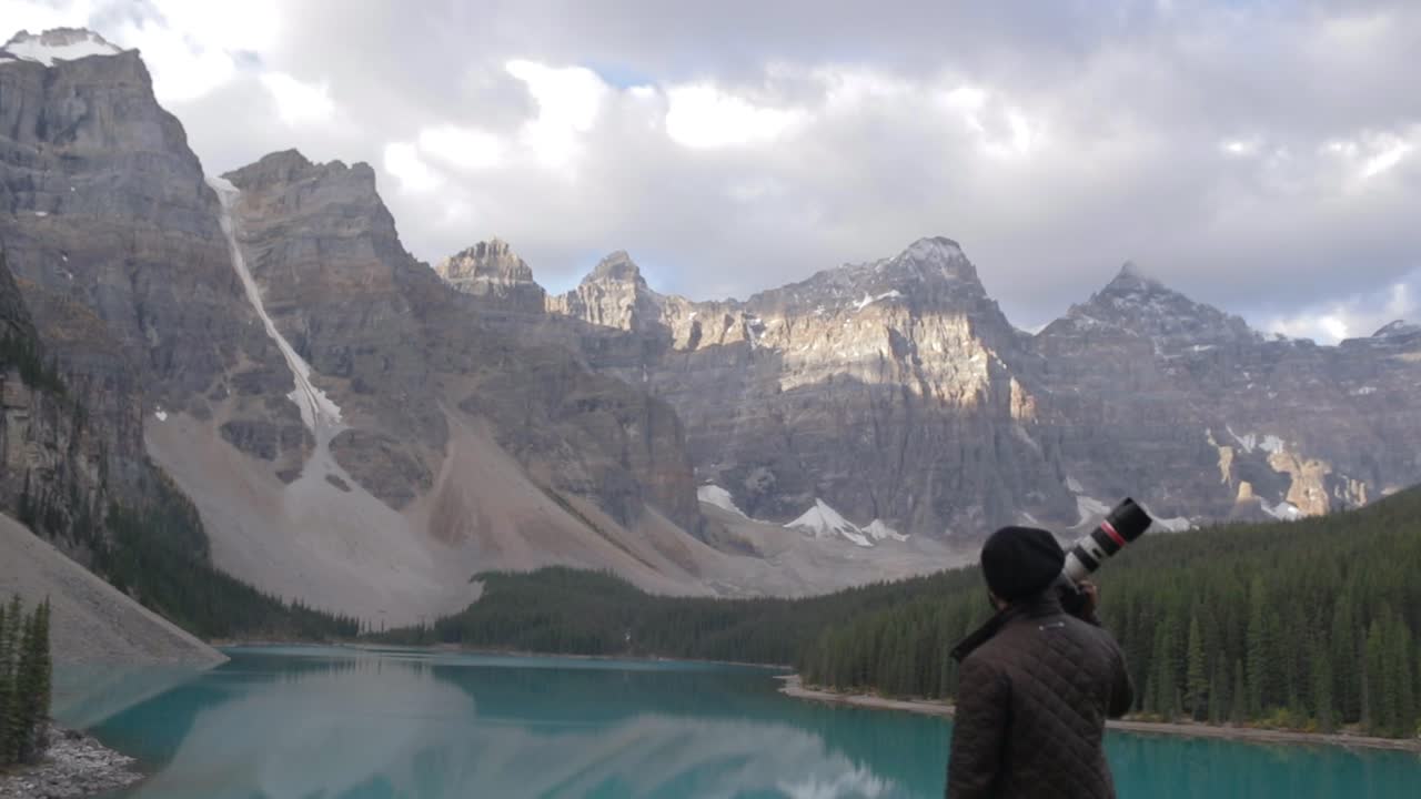 un fotógrafo de viajes parado cerca de un lago azul en banff, canadá