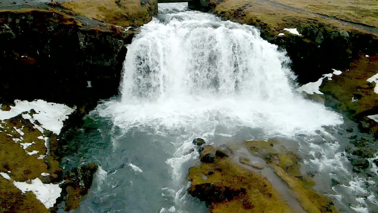 un avión no tripulado de 4k distante, aéreas, cinematográficas, tomas únicas de agua que fluye rápidamente desde la distancia en islandia