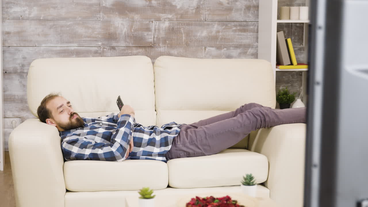 Man relaxing on couch with remote in living room
