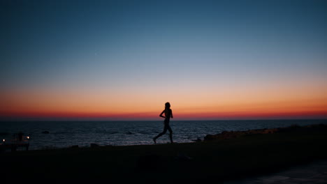 silhouette of a woman running on the beach at sunset