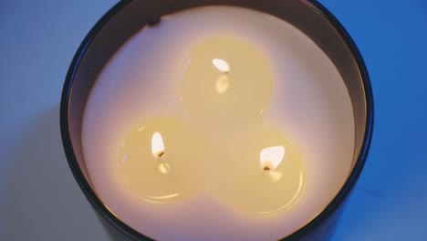 white candle in a glass with three lit wicks