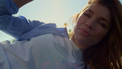 hermosa mujer tocando el cabello rubio salvaje en la luz del atardecer en el fondo del cielo azul.