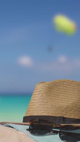 video vacaciones de verano verticales concepto de gafas de sol sombrero de playa toalla en la arena contra el mar con parapente