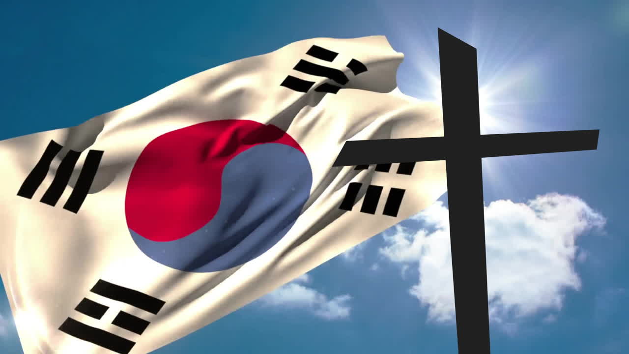 Waving South Korean flag next to large black cross under clear blue sky
