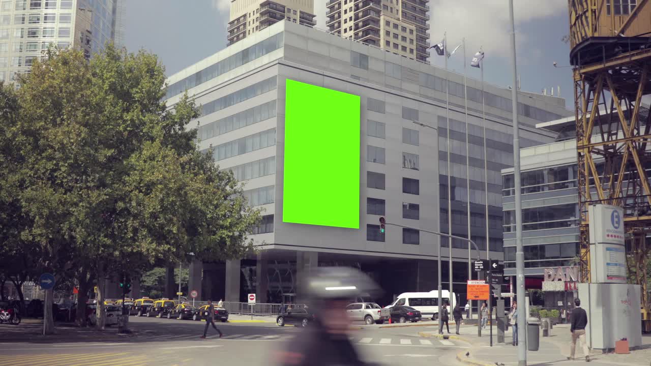 Cartellone green screen su un moderno edificio cittadino con pedoni e traffico.