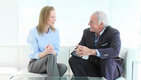 una mujer de negocios y un hombre de negocios hablando en un sofá.