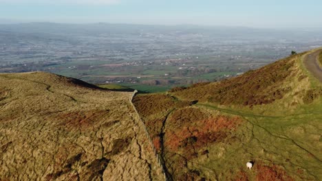 la primera luz del sol en el pico de la montaña de las tierras altas vista aérea a través del vasto norte de gales heladas idílicas tierras de cultivo campo órbita izquierda