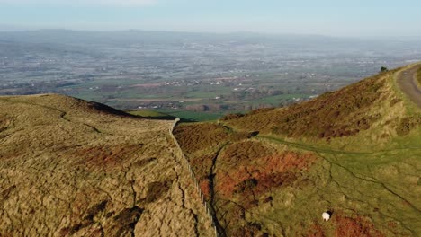 early sunlight on highland mountain peak aerial view across vast north wales frosty idyllic farmland countryside orbit left