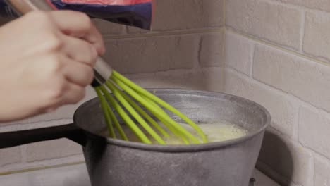 hands pouring polenta in saucepan - close up